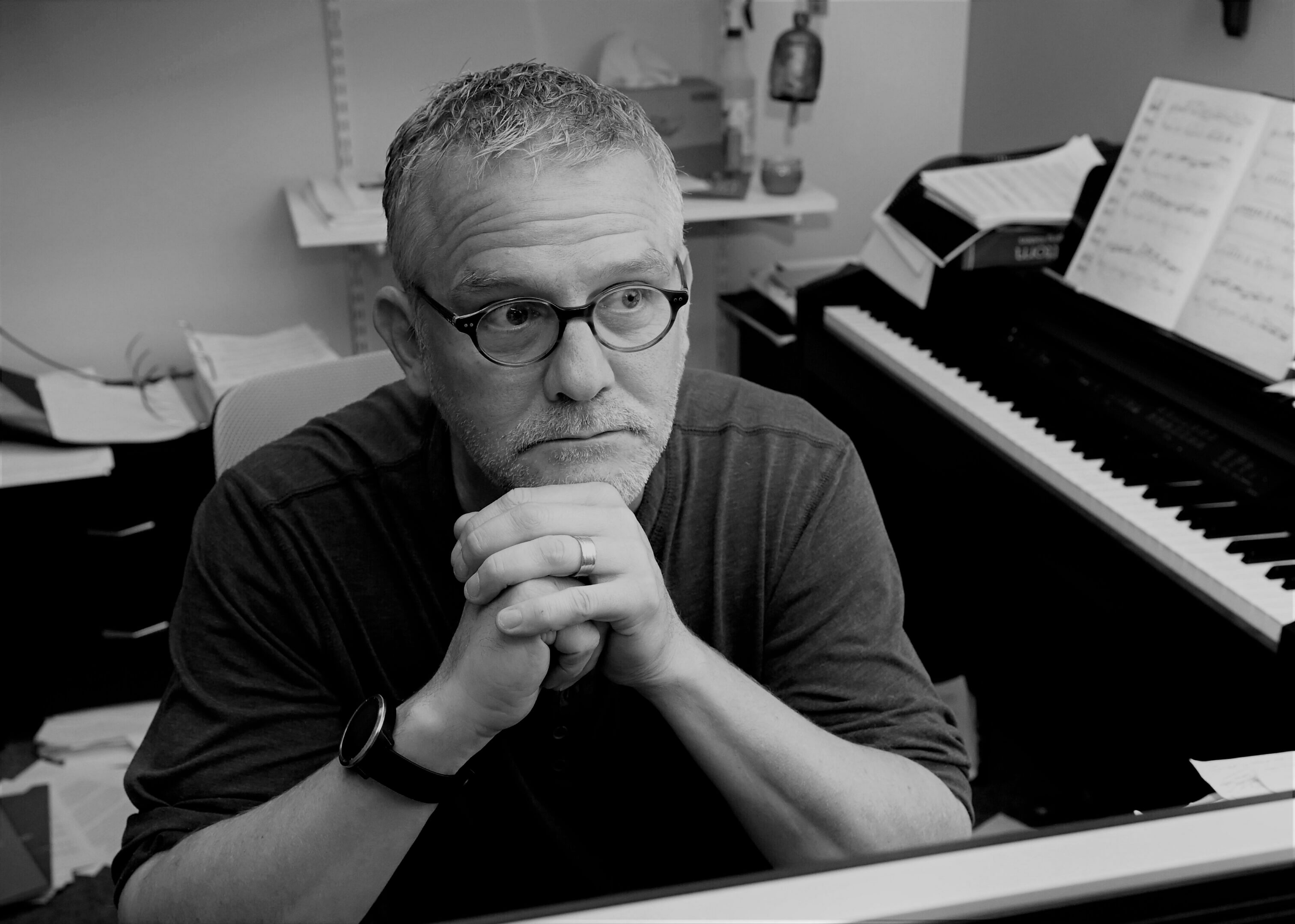 Man thinking beside piano in office.