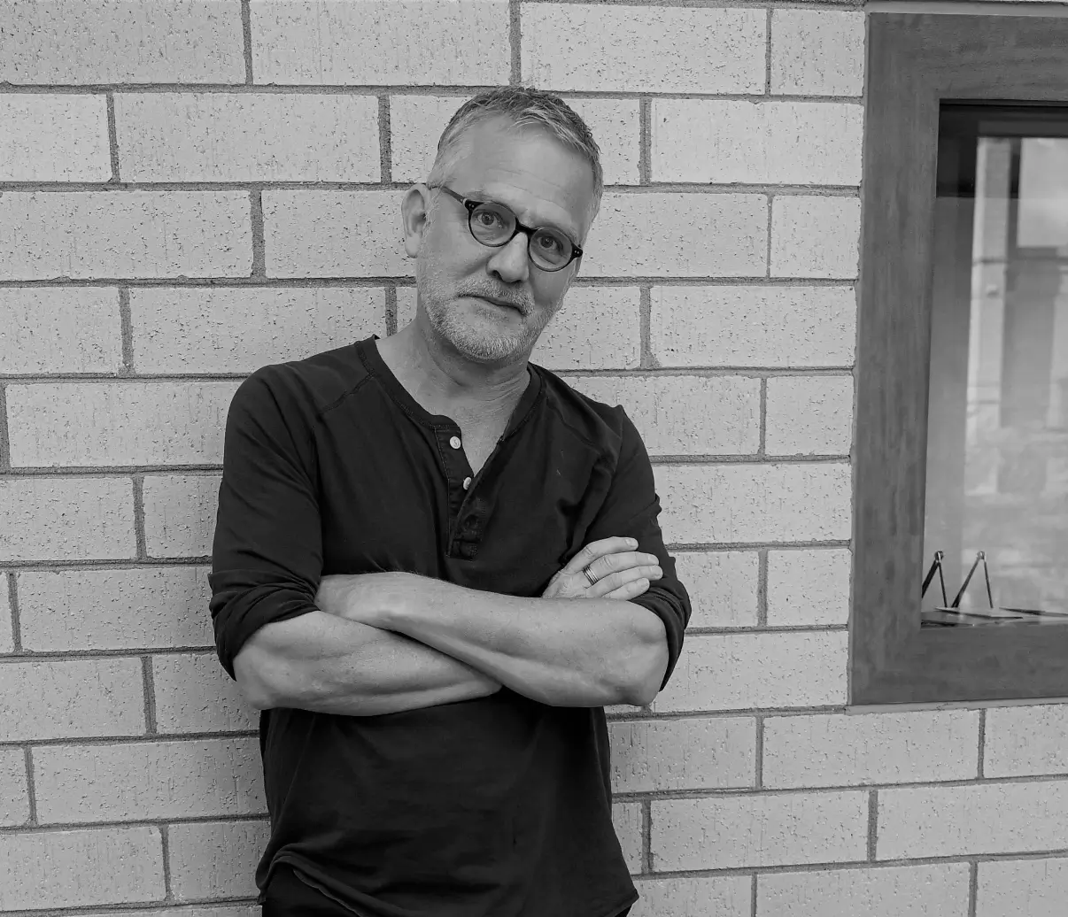 Man leaning against brick wall, arms crossed.
